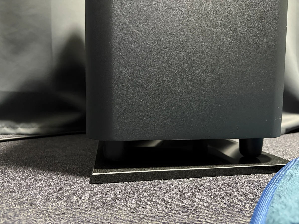 ラグの上の石製オーディオボードに設置したJBL BAR1000のサブウーファー